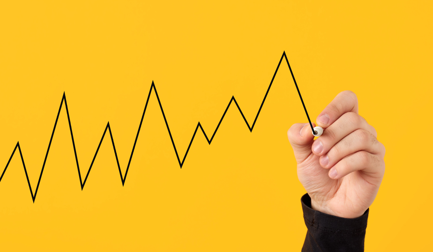 Male hand draws a fluctuating line graph on yellow background. Business, economy and finance concept.